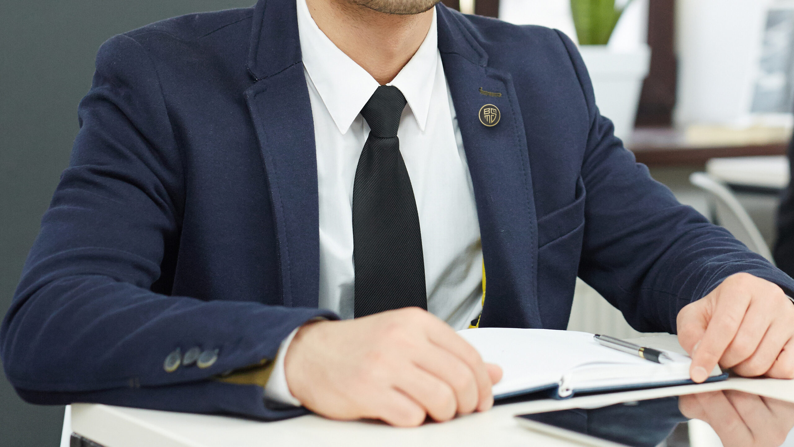 Young serious businessman with notebook and tablet sitting by desk